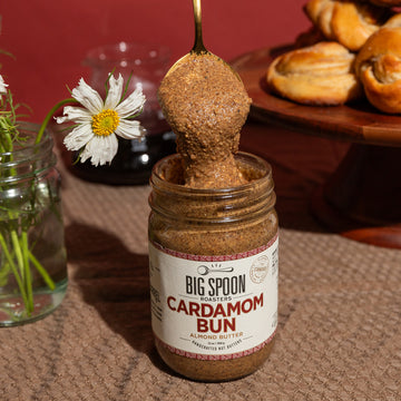 Spoon pulls a spoonful of Almond Butter from the top of a jar of Cardamom Bun Almond Butter