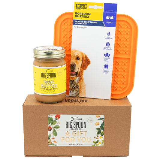 Jar of Banana Flax Wag Butter and an orange Boredom Busters Lick Mat on top of a gift box