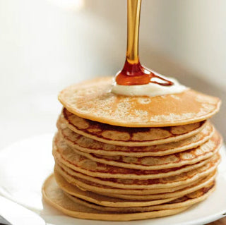 Maple Cinnamon Pecan Pancakes with syrup being drizzled overtop. 