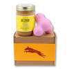 Jar of Banana Flax Wag Butter and a pink West Paw Tux toy sit on top of a gift box with a gold and maroon decorative dog label.