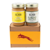 A jar of Banana Flax Wag Butter sits next to a jar of Almond Butter on top of a gift box