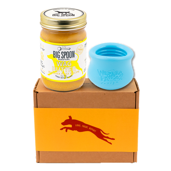 Jar of Banana Flax Wag Butter and a blue West Paw Toppl toy on top of a gift box