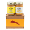 A jar of Banana Flax Wag Butter sits next to a jar of Peanut Butter on top of a gift box