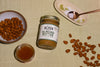 a jar of Almond Butter surrounded by a bowl of almonds, a jar of honey, sea salt, and other almonds