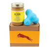 Jar of Banana Flax Wag Butter and a blue West Paw Tux toy sit on top of a gift box with a gold and maroon decorative dog label.